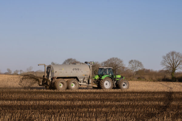 A tractor fertilizing brown field